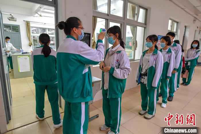 海南华侨中学学生在进入教室前有序测量体温。 骆云飞 摄  海南高三、初三开学 单人单桌上课错时就餐