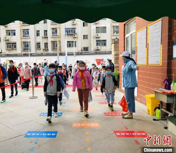 郑州市金水区金燕小学的小学生脚踩一米间隔线排队入校 杨晨 摄  河南多地小学今返校复学 校园教学活动渐入正轨